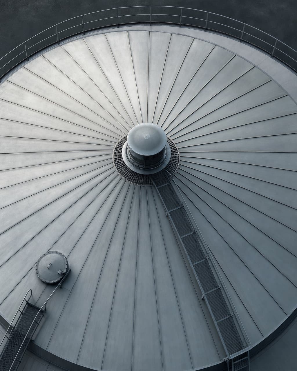The cone roof of a storage tank seen from above, plates radiating from a central vent with a gauge hatch